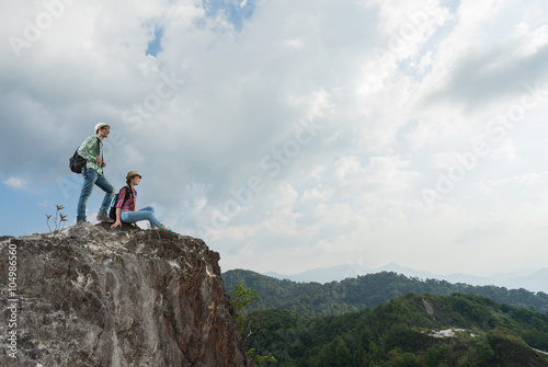 Travel concept. Young tourists with backpacks enjoying valley view from top of a mountain