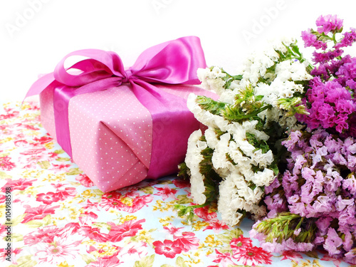 pink gift box with ribbon and flower bouquet on printed fabric background © may1985
