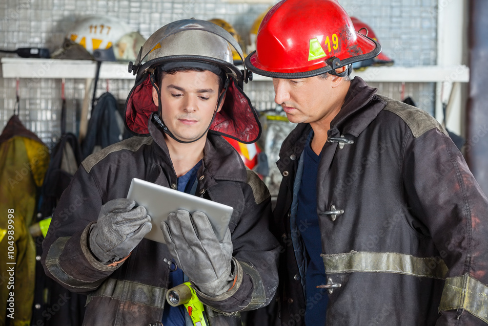 Obraz premium Firefighters Using Digital Tablet At Fire Station