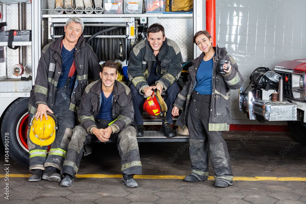Naklejka premium Portrait Of Confident Firefighters By Truck