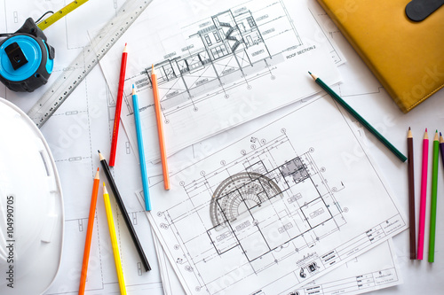 Image of blueprints with level pencil and hard hat on table