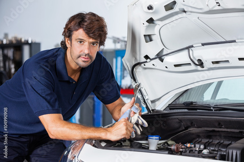 Confident Mechanic Leaning On Car With Open Hood