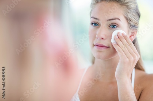 Woman wiping her face with cotton pad