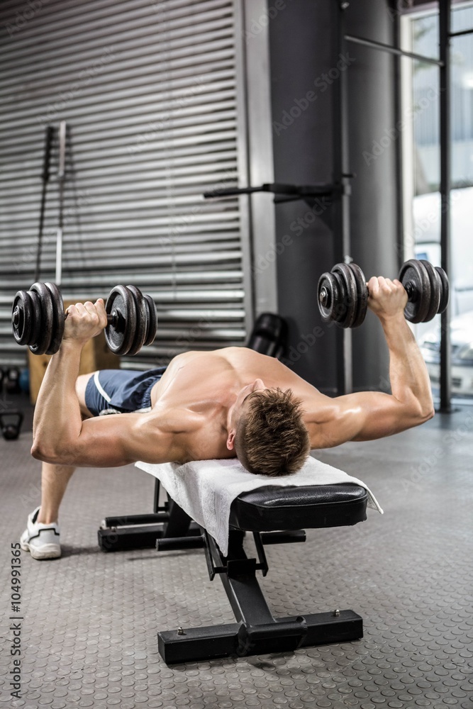 Shirtless man lifting heavy dumbbells on bench Shirtless man lifting heavy dumbbells on bench