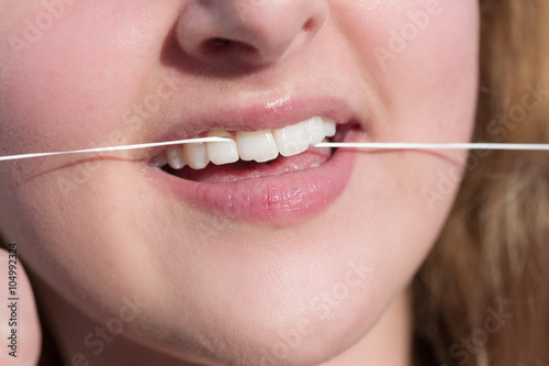 Junge Frau benutzt Zahnseide zur Zahnreinigung