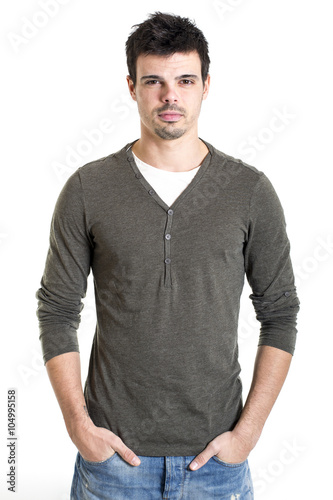 Serious young man with hands in pockets on white background