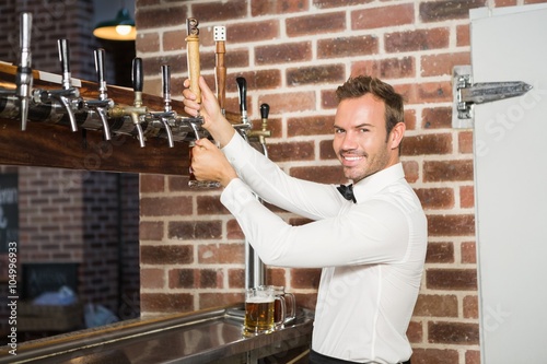Photos Handsome barman pouring a pint of beer