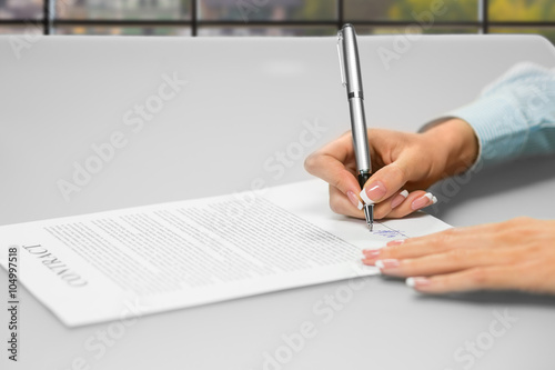Woman's hands signing office papers.