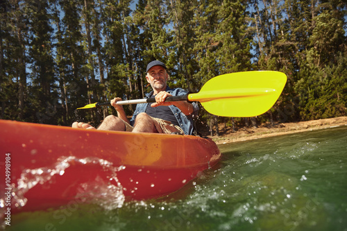 Mature man canoeing on summer day photo