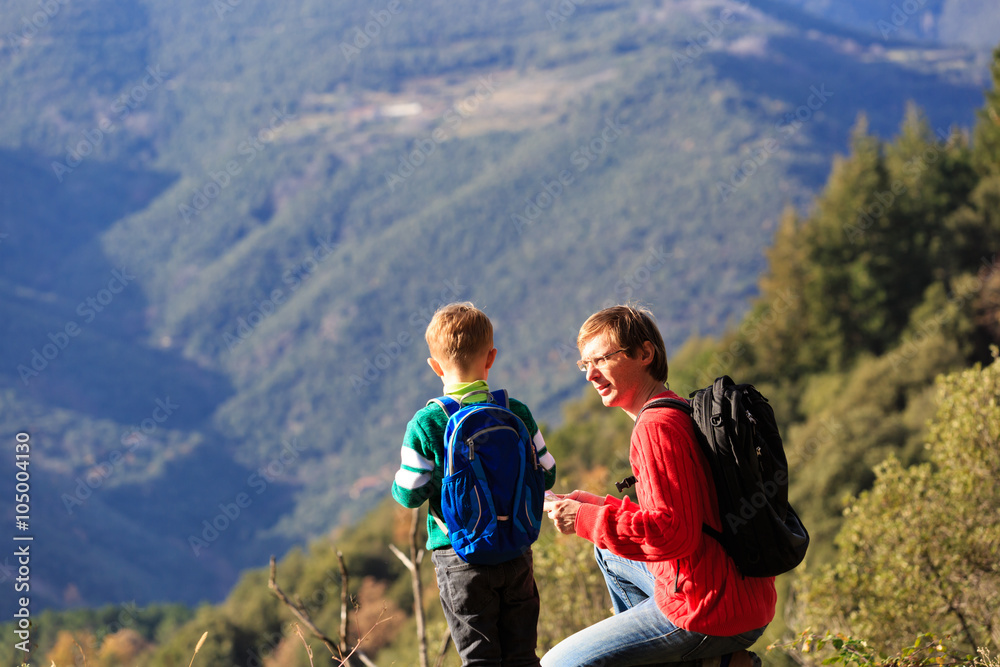 father and son travel in mountains looking at map