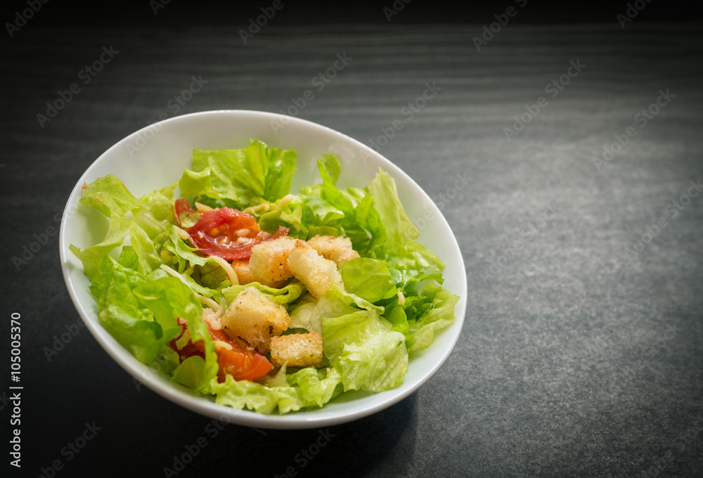 Caesar salad made of fresh vegetables on dark background. Selective focus.