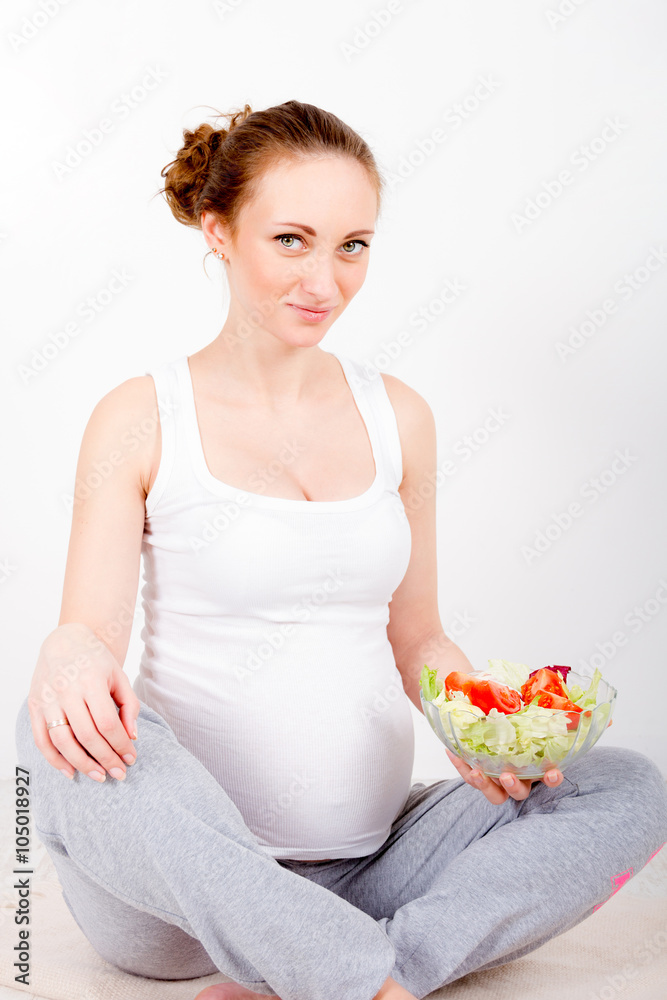 Beautiful young pregnant woman / teenager in white cloth eating healthy fresh salad with vegetebles Beautiful young pregnant woman / teenager in white cloth eating healthy fresh salad with vegetebles