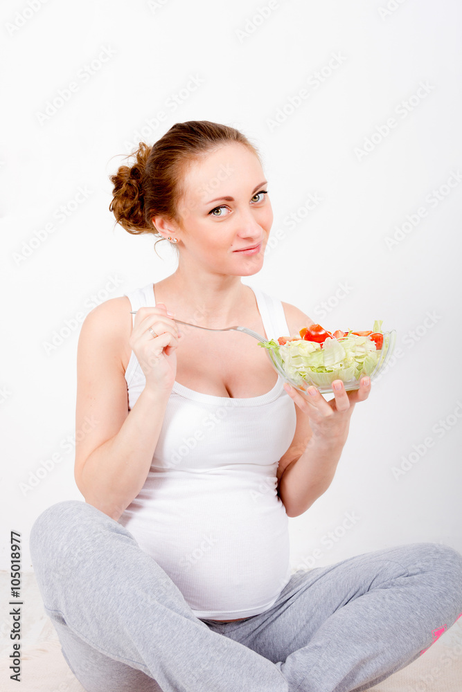 Beautiful young pregnant woman / teenager in white cloth eating healthy fresh salad with vegetebles Beautiful young pregnant woman / teenager in white cloth eating healthy fresh salad with vegetebles