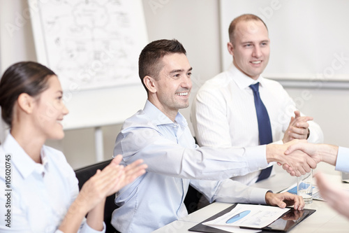 smiling business team shaking hands in office