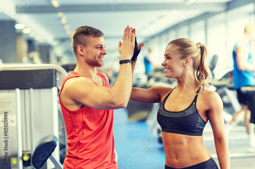 smiling man and woman doing high five in gym