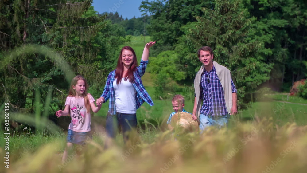 Family is walking near wheat field and waving to the farmer Family is walking near wheat field and waving to the farmer