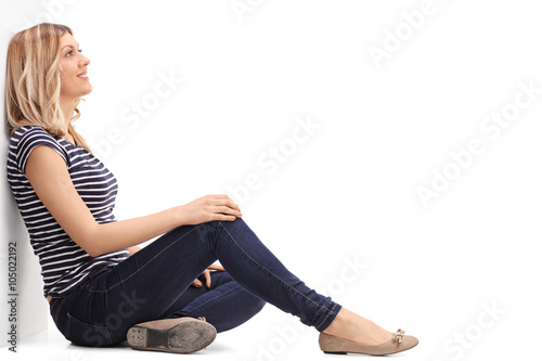 Pensive blond woman leaning against a wall