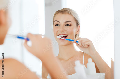 woman with toothbrush cleaning teeth at bathroom