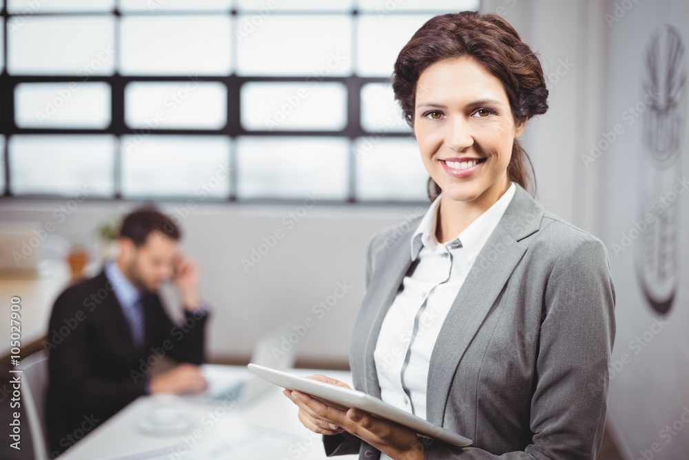 Businesswoman using tablet while colleague in background Businesswoman using tablet while colleague in background