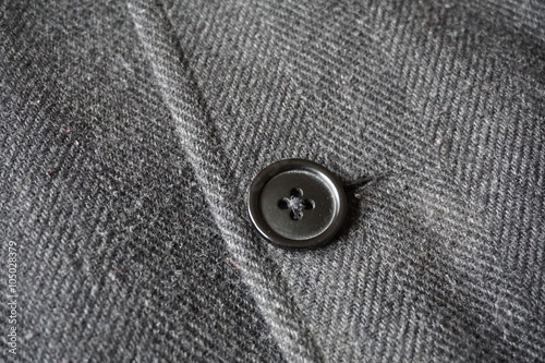 Detail of a dark button fastening the fish bone winter coat 