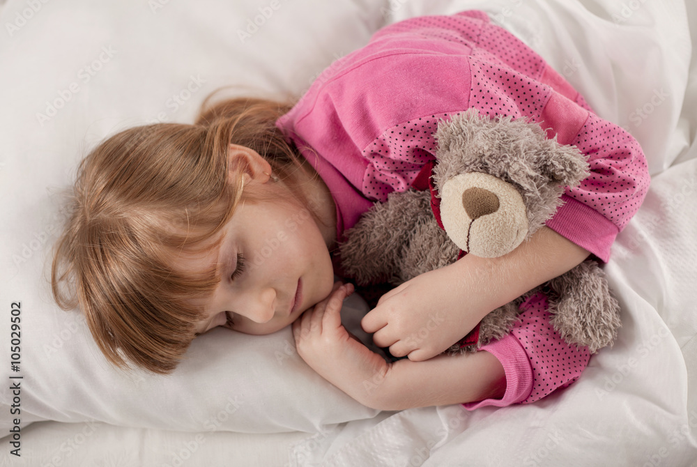 Adorable little girl sleeping in the bed with her toy Adorable little girl sleeping in the bed with her toy