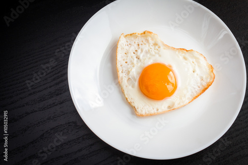 Fried egg in form of heart on a black background