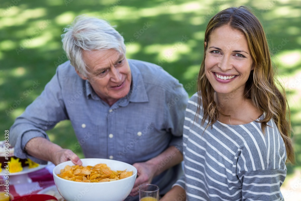 Senior man offering crisps to young woman Senior man offering crisps to young woman