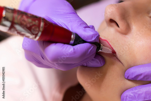 Cosmetologist applying permanent makeup on lips
Selective focus and shallow Depth of field
 photo