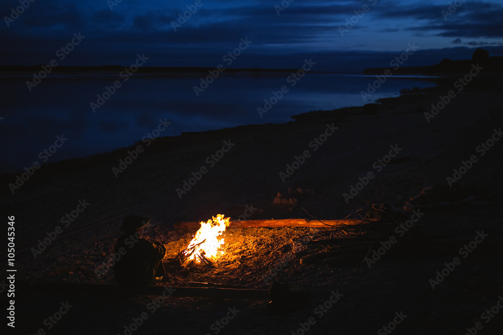 Silhouette of tourist girl around the campfire at night on the river shore Silhouette of tourist girl around the campfire at night on the river shore
