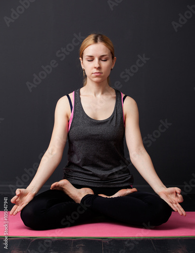 Young woman is sitting in the lotus pose with closed eyes