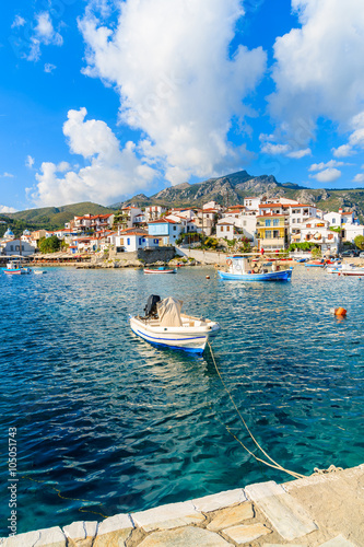 Fishing boat in Kokkari port with colorful houses in background, Samos island, Greece
