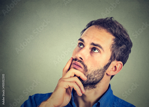 man resting chin on hand thinking daydreaming, staring thoughtfully upwards