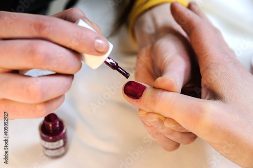 Manicurist is applying nail varnish.