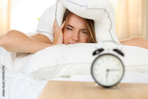 Canvas Print Young beautiful blonde woman lying in bed suffering from alarm c