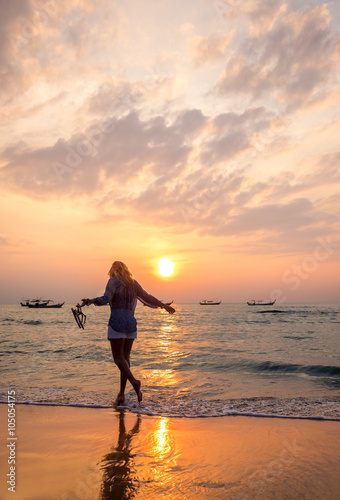 carefree woman dancing in the sunset on the beach