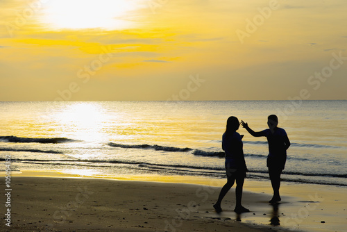 Two women greet each other on the beach at sunset.