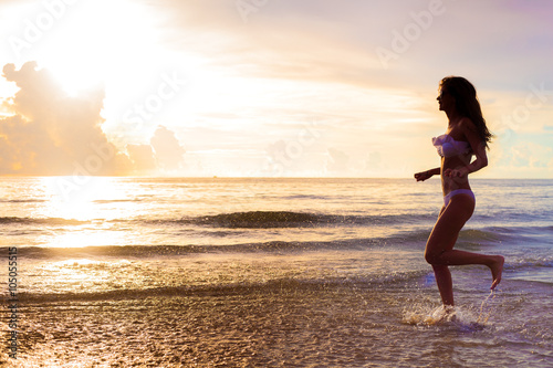 carefree woman running in the sunset on the beach. vacation vitality healthy living concept. water drops