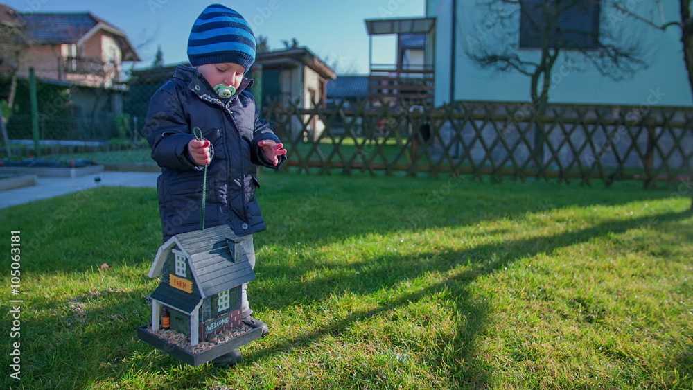 Little child is lifting up a small wooden bird house Little child is lifting up a small wooden bird house