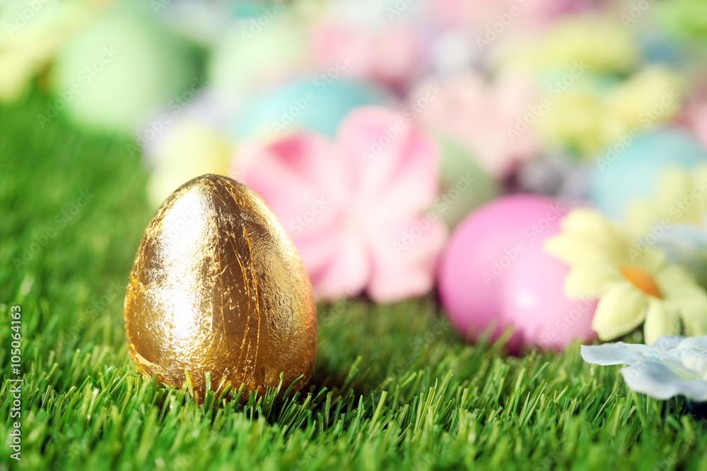Obraz premium Colorful Easter eggs on grass with golden egg