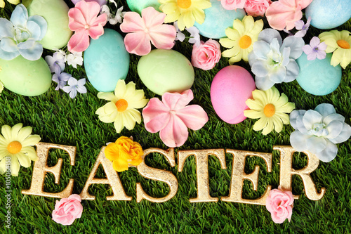 Colorful Easter eggs on grass with flowers background