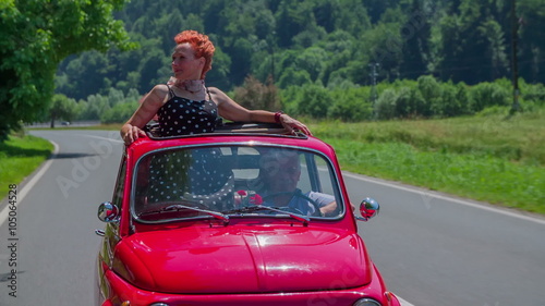 A senior lady observing the landscape when driving in a red yugo photo