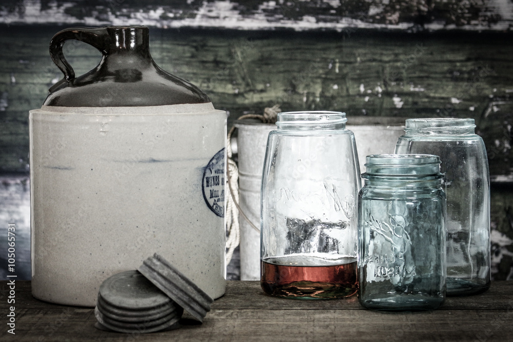 Vintage crock jug with mason jars, one with bourbon or whiskey within