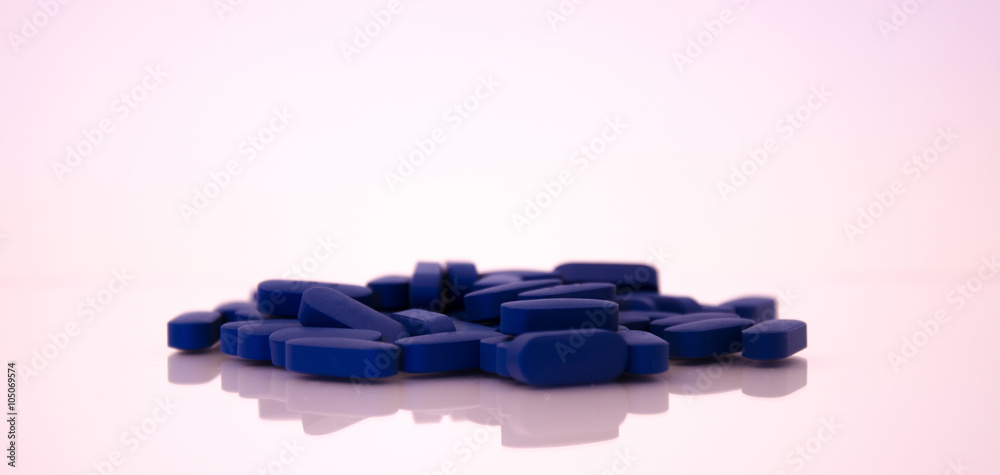 Long Blue Pills on a Reflective White Background