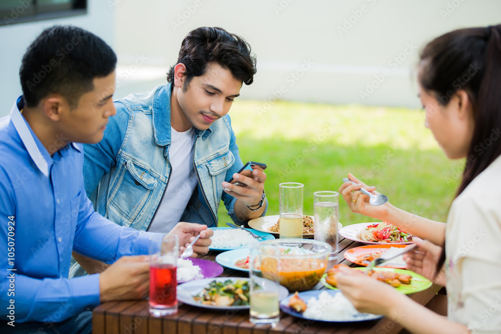 Asian man sitting on a smartphone during the meal. Group with fr Asian man sitting on a smartphone during the meal. Group with fr