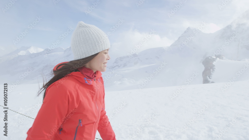 Woman walking in Swiss alps Switzerland on top of Jungfrau mountain next to Aletsch glacier. Female hiker hiking in snow in summer in the Swiss alps. Mixed race Asian Caucasian girl.
