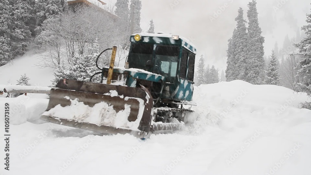 Tractor cleans snow-covered road during a snowfall Tractor cleans snow-covered road during a snowfall