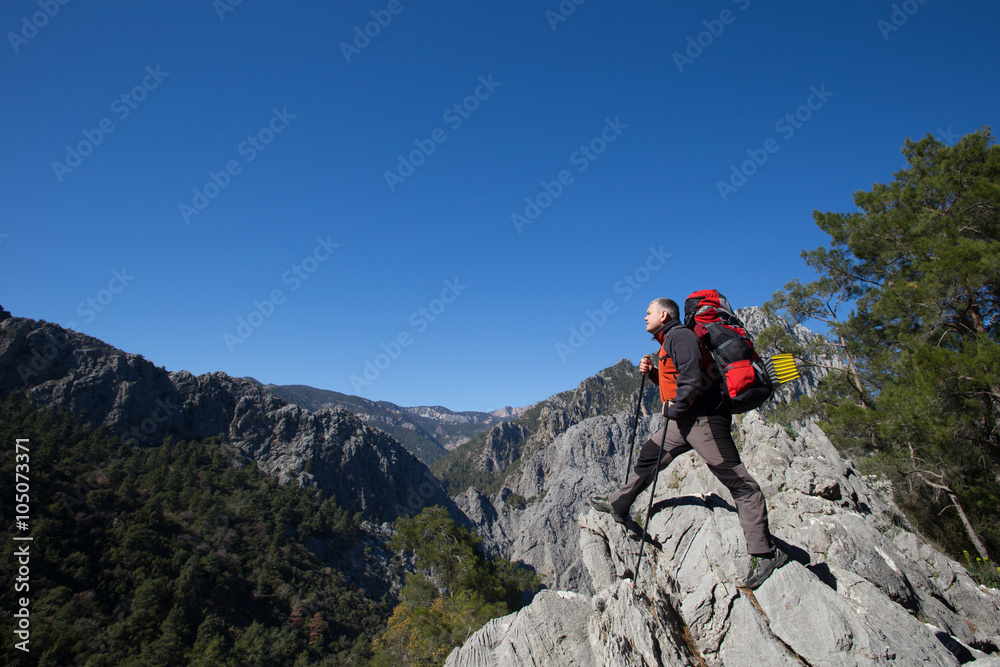 Hiker standing on top of the mountain with valley on the background. Hiker standing on top of the mountain with valley on the background.
