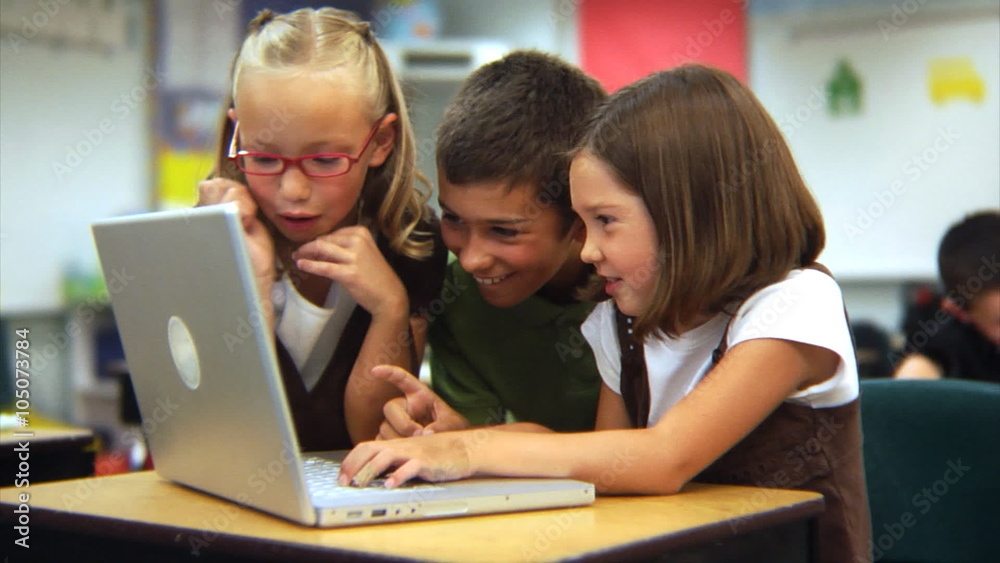 Elementary school students looking at laptop computer Elementary school students looking at laptop computer
