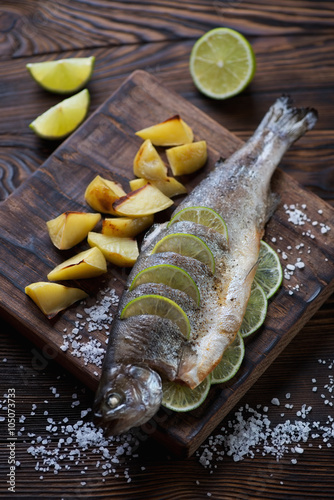 Baked trout fish with potato on a rustic wooden serving board
