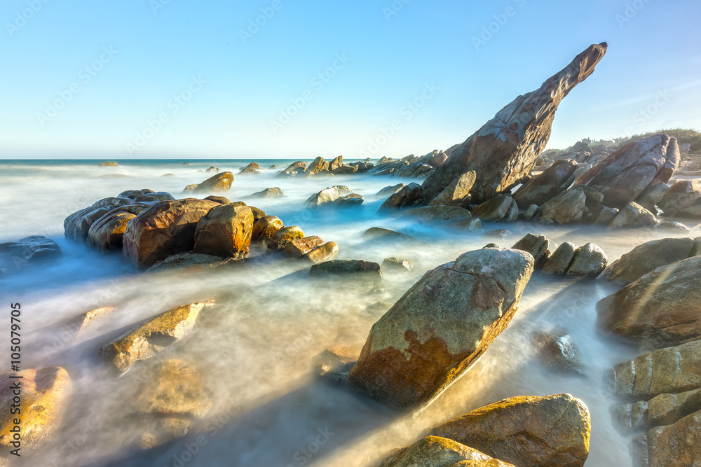 Volcanic rocks beach with waves smooth stone architecture as construction poppers matrix in one direction, below smooth waves after receiving afternoon sun on desolate seas in Vietnam